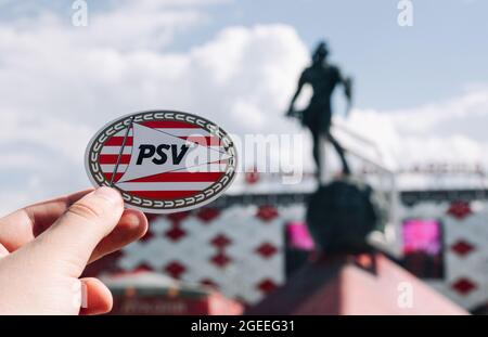 14. Juni 2021 Eindhoven, Niederlande. Das Emblem des Fußballvereins PSV Eindhoven vor dem Hintergrund eines modernen Stadions. Stockfoto