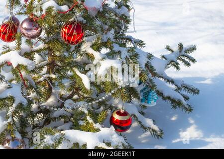 Schöner kleiner Weihnachtsbaum, der an einem verschneiten Wintertag mit Spielzeug und Perlen geschmückt ist. Wir Feiern Weihnachten. Stockfoto