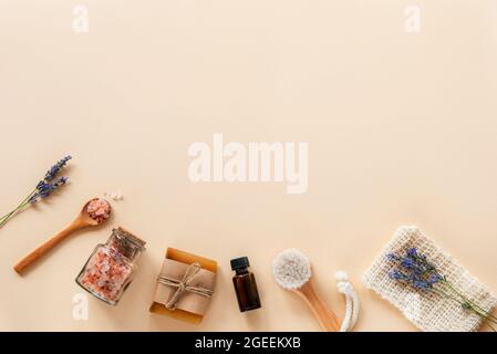 Badaccessoires und Naturkosmetik, himalaya-Rosa-Salz im Glas, ätherisches Öl, Seife und Lavendelblüten auf beigem Hintergrund. Keine Verschwendung Stockfoto