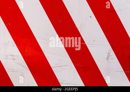 Verblasste rote und weiße diagonale Stechstreifen auf flachem Stahlblech - Warnschild Stockfoto