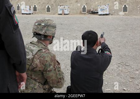 Ein in der Stadt Khost stationierter afghanischer uniformierte Polizist feuert eine M-9-Beretta-Pistole auf einen kleinen Waffenbereich im Lager Parsa, Provinz Khowst, Afghanistan, 30. Januar 2013. Soldaten der US-Armee, die dem Team 28 der Sicherheitskräfte, der Task Force 3/101, zugewiesen wurden, planten die Reichweite und unterstützten die AUP beim sicheren Üben mit ihren Waffen. (USA Armeefoto von Sgt. Kimberly Trumbull / Veröffentlicht) Stockfoto