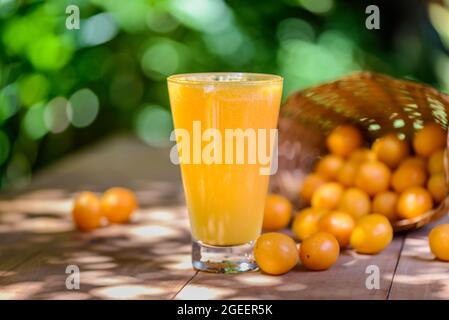 Brasilianischer obstkaja. Ein Glas Saft auf einem Holztisch. Stockfoto
