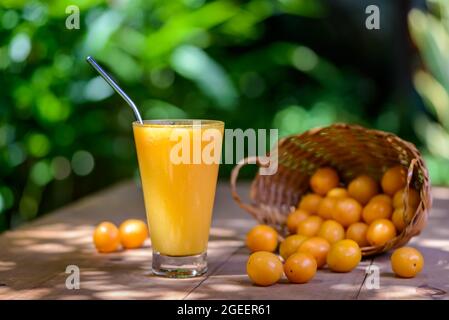 Brasilianischer obstkaja. Ein Glas Saft auf einem Holztisch. Stockfoto