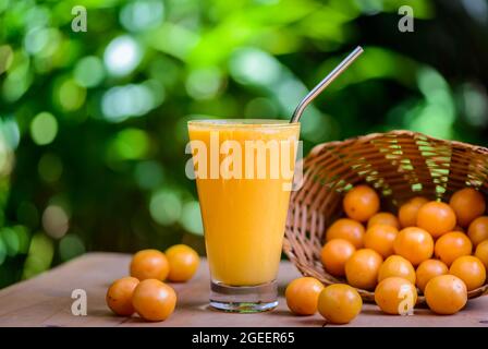Brasilianischer obstkaja. Ein Glas Saft auf einem Holztisch. Stockfoto