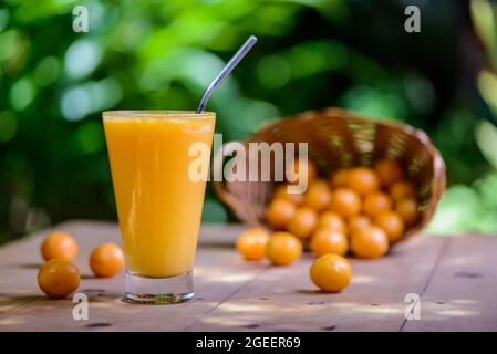 Brasilianischer obstkaja. Ein Glas Saft auf einem Holztisch. Stockfoto
