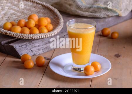 Brasilianischer obstkaja. Ein Glas Saft auf einem Holztisch. Stockfoto
