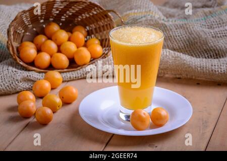 Brasilianischer obstkaja. Ein Glas Saft auf einem Holztisch. Stockfoto