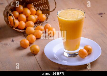 Brasilianischer obstkaja. Ein Glas Saft auf einem Holztisch. Stockfoto