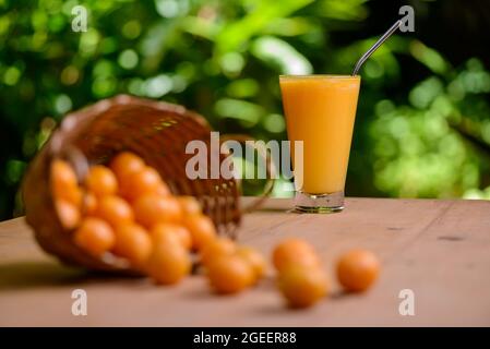 Brasilianischer obstkaja. Ein Glas Saft auf einem Holztisch. Stockfoto