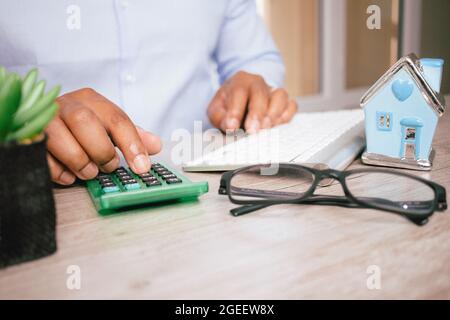 Nahaufnahme der Hände eines hispanischen Geschäftsmannes, während er einen Rechner an seinem Schreibtisch mit Brille darauf verwendet Stockfoto