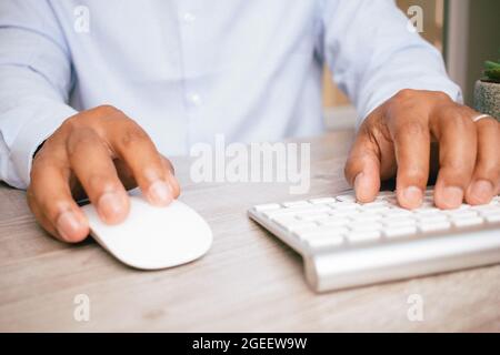 Nahaufnahme der Hände eines hispanischen Geschäftsmannes, der eine Computermaus und eine Tastatur verwendet Stockfoto