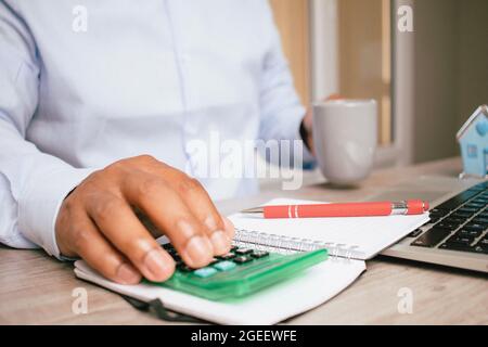 Nahaufnahme der Hände eines hispanischen Geschäftsmannes, während er in seinem Büro einen Rechner verwendet Stockfoto