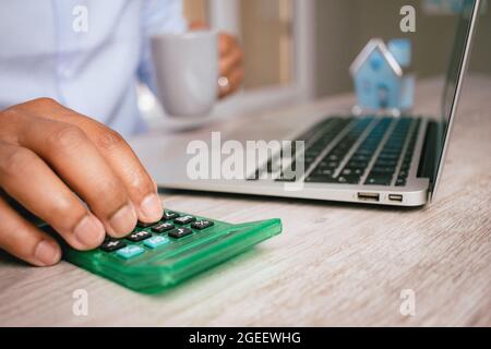 Nahaufnahme der Hand eines hispanischen Mannes, der in seinem Büro einen Rechner auf einem verschwommenen Hintergrund verwendet Stockfoto