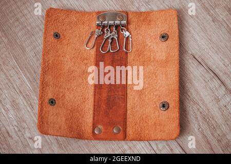 Nahaufnahme eines geöffneten braunen Lederschlüsselhalters auf einem Holztisch Stockfoto