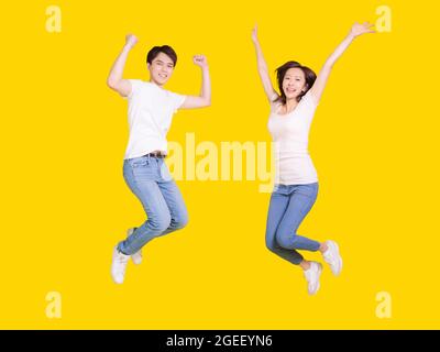 Glückliches Paar springen.Junge Mann und Frau, die Spaß zusammen haben.isoliert auf gelbem Hintergrund. Stockfoto