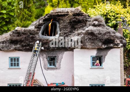 Nahaufnahme eines winzigen Modellhauses mit dem Dach in Flammen Stockfoto