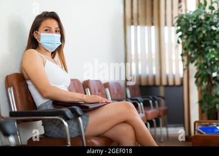 Junge Frau in Schutzmaske wartet auf Vorstellungsgespräch Stockfoto
