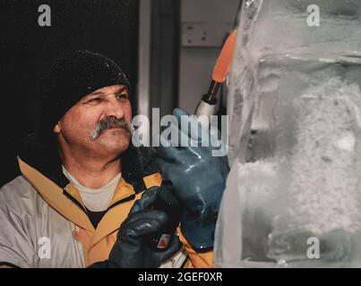 Professioneller Eisschnitzer, der Eisklotz modelliert Stockfoto