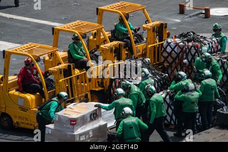 210819-N-UF592-1142 ARABIAN SEA (AUG 19, 2021) – Seeleute bereiten Fracht für den Transport auf dem Flugdeck des Flugzeugträgers USS Ronald Reagan (CVN 76) in der Arabischen See vor, 19. August. Ronald Reagan ist das Flaggschiff der Carrier Strike Group 5 und wird im Einsatzgebiet der 5. US-Flotte zur Unterstützung von Marineoperationen eingesetzt, um die maritime Stabilität und Sicherheit in der Zentralregion zu gewährleisten. Verbindung des Mittelmeers mit dem Pazifik durch den westlichen Indischen Ozean und drei strategische Engpässe. (USA Navy Foto von Mass Communication Specialist Seaman Eric Stanton) Stockfoto