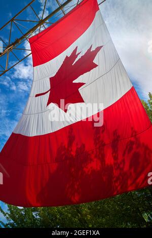 Große kanadische Flagge in der Sonne. EINE große kanadische Flagge hängt an einem sonnigen Tag im Freien. Kanada. Stockfoto