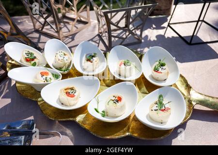 Snacks in weißen Schalen auf einem goldenen Teller in Form des Baumblattes Stockfoto