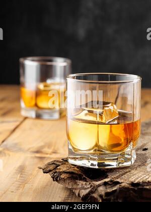 Zwei Gläser mit Eiswürfel und Whiskey auf einem alten Holztisch. Speicherplatz kopieren. Stockfoto