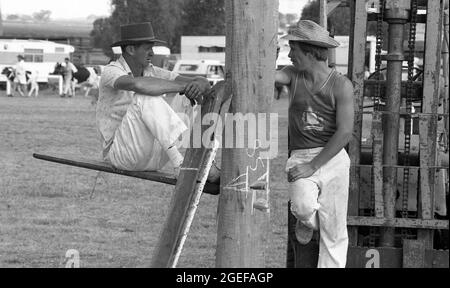 QUEENSLAND, AUSTRALIEN, MAI 1984: Zwei unbekannte Männer diskutieren bei einer jährlichen Country Town A und P Show 1984 über die Taktik für das bevorstehende Holzhacken-Event. Der ältere Mann sitzt auf einem Jigger Board, das zum Klettern des Pfostens zum Hackblock oben am Pfosten verwendet wird. Gescannt von Originalnegativen für die Zeitungsveröffentlichung. Stockfoto