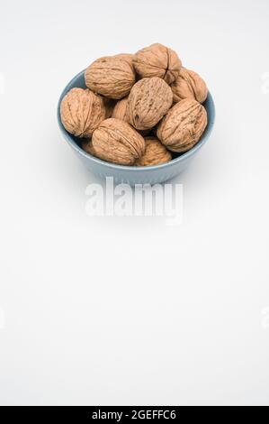 Vertikale Aufnahme von ganzen Walnüssen in einer blauen Schale isoliert auf weißem Hintergrund Stockfoto