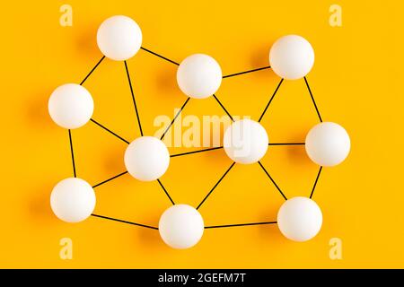 Miteinander verbundene Kugeln repräsentieren eine Netzwerkstruktur. Kommunikations-, Verbindungs- oder Vernetzungskonzept. Stockfoto