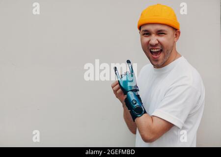 Junger behinderter Mann mit einer Gestik aus Steinziegen und künstlicher prothetischer Hand in legerer Kleidung Stockfoto