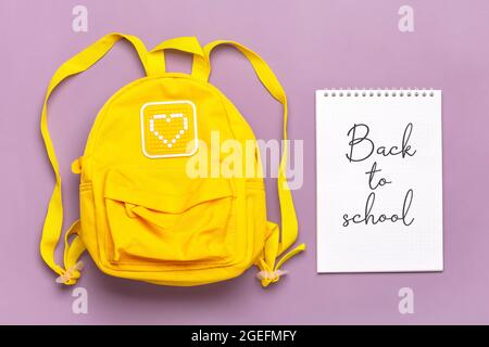 Zurück zum Schultext auf offenem Notizblock, Bildungskonzept. Gelber Rucksack auf gewalttätigem Hintergrund isoliert. Draufsicht Flat Lay Komposition Student Stockfoto