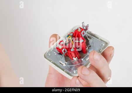 Mann, der eine Computersteckdose vor einem weißen Hintergrund hält. Internet-Buchse für Twisted-Pair-Kabel. Reparaturen, Austausch der Kommunikation. Stockfoto