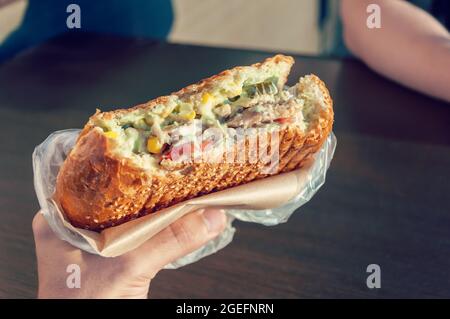 Nahaufnahme der Hand mit Fajitas-Füllung mit Salatsalat, Speck, Tomaten, Saucen, Käse und Gemüse. Stockfoto