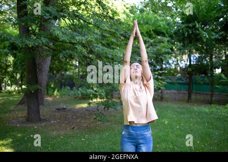 Indische Frau, die im Sommerpark im Freien Yoga macht. Stockfoto