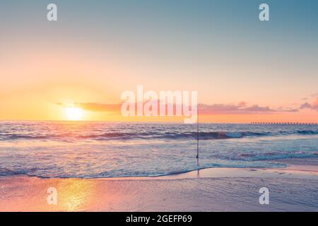 Surfen Sie an einem Sandstrand bei Sonnenuntergang, South Australia, mit Angelrute Stockfoto