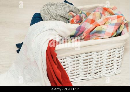 Schmutzige Bettwäsche in einem weißen Korbkorb auf dem Boden Stockfoto