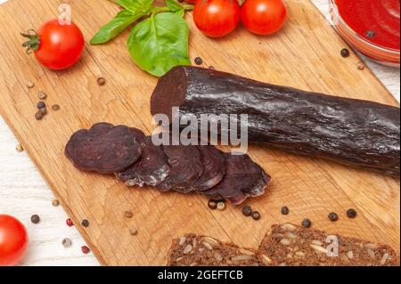 Pferdefleischwurst mit Tomaten und Kräutern auf einem Holzbrett Stockfoto