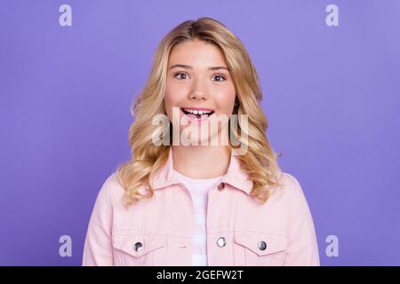Foto von beeindruckt charmante Schulmädchen gekleidet rosa Kleidung offenen Mund lächelnd isoliert lila Farbe Hintergrund Stockfoto