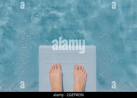 Die Füße der Frau auf einem Sprungbrett in einem privaten Pool zu Hause, während eines Aufenthalts im Sommer Stockfoto