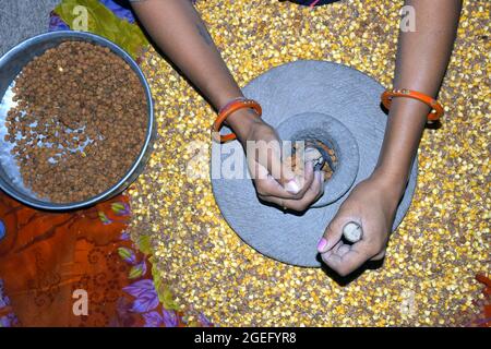 Die Hand einer Dorffrau mahlt in einer alten, handbetriebenen Mehlmühle Gramm. Stockfoto