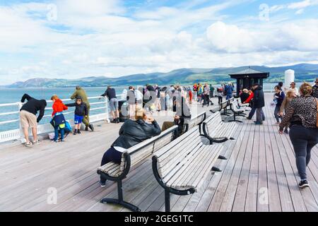 Touristen und Besucher genießen einen Sommernachmittag am Beaumaris Pier, einer beliebten Touristenattraktion am Meer auf der Insel Anglesey Stockfoto