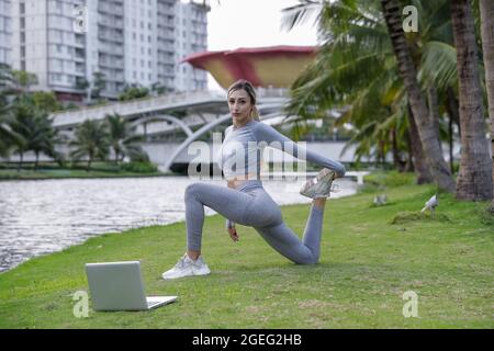 Junge, frecher Frau macht Dehnübungen im öffentlichen Park. Sportliche und starke Mädchen trainieren. Fitness-Training im Freien. Freizeitkonzept. Stockfoto