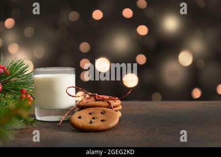 Hausgemachte Weihnachtskekse und ein Glas Milch für den Weihnachtsmann auf der festlichen Tischplatte. Weihnachtsfeiertag. Stockfoto