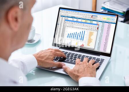 Geschäftsmann, Der Mit Tabellenkalkulationsgrafiken Auf Dem Computer Arbeitet Stockfoto