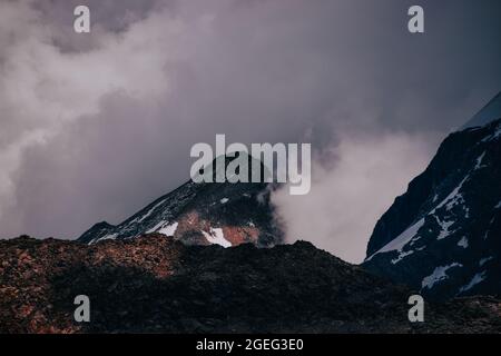 Verschneite Berggipfel unter dem trüben dunklen Himmel im Nationalpark Gran Paradiso in Italien Stockfoto
