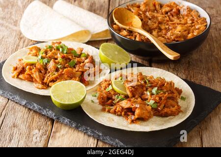 Mexikanisches geschreddertes Schweinefleisch Chilorio Tacos in der Nähe in der Schiefertafel auf dem Tisch. Horizontal Stockfoto