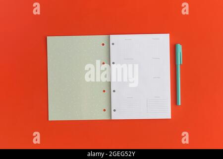 Notizbuch und Stift auf rotem Hintergrund. Draufsicht. Flach liegend. Zurück zum Schulkonzept. Stockfoto