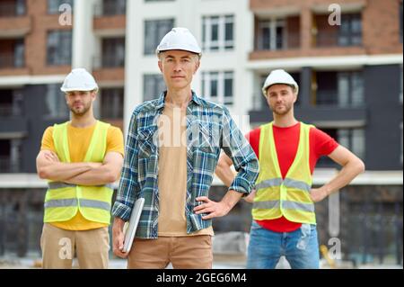Drei Männer in Schutzhelmen stehen auf der Baustelle Stockfoto