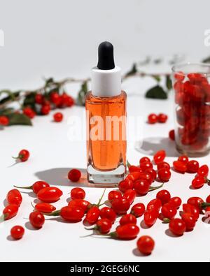 Goji-Beerensamenöl in Glasflasche und frische Goji-Beeren auf dem Tisch. Stockfoto