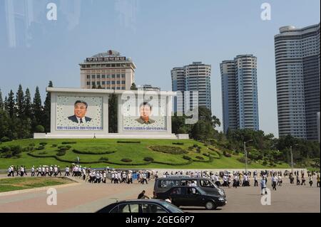 08.08.2012, Pjöngjang, Nordkorea, Asien - Fußgänger gehen an zwei riesigen tableau-Gemälden vorbei, auf denen die Porträts der verstorbenen nordkoreanischen Führer abgebildet sind. Stockfoto